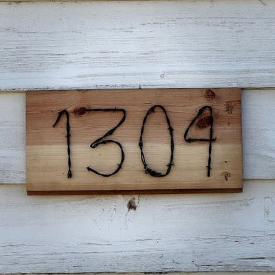 Wooden house number sign with '1304' on a white wall.